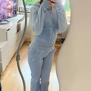 Classic Velour Juicy Coutore  - Säljer ett par ljusblå mjukisbyxor i mjukt velourmaterial. Byxorna har bred resår i midjan, stora fickor med lock och knappdetalj på sidorna samt raka ben. Perfekta för chill och mysiga dagar hemma. Tröjan är o storlek XS och byxorna i XXS. Snöret till byxorna har jag tagit ut men sckikas med i paketet. Köpa på Juicy Coutores egna sida för 2500.