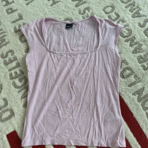 Ljusrosa topp från Gina Tricot - Säljer en ljusrosa topp från Gina Tricot i mjuk bomull. Toppen har en rundad, lite djupare urringning och är ärmlös med smala axelpartier. Perfekt för varma dagar eller som layering-piece.