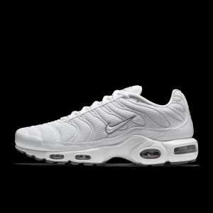 Nike Air Max Plus vita sneakers - Nike Air Max Plus i helvitt med mesh och syntetpaneler, ikoniska vågformade detaljer och synliga Air Max-enheter i sulan. Snygg design med grå och svarta detaljer på yttersulan och klassisk Nike-logga på sidan. Perfekta för dig som gillar streetstyle och komfort.