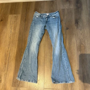 Blå low waist bootcut jeans från Gina Tricot - Snygga ljusblå jeans från Gina Tricot i bootcut-modell. Klassisk femficksdesign med dragkedja och knapp framtill. Jeansen har en lätt tvättad look och är tillverkade i mjukt bomullsmaterial. Perfekta för dig som gillar retrovibbar och bekväm passform.