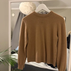 Beige kashmirtröja från Stockh LM - Säljer en mjuk och lyxig beige kashmirtröja från Stockh LM i storlek S. Tröjan har rund hals, ribbade muddar och lång ärm. Perfekt för dig som gillar stilrena och klassiska plagg med skön känsla.