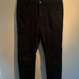 Svarta jeans från Riley  - Svarta jeans med klassisk femficksdesign och smal passform. Byxorna har knapp och dragkedja framtill samt raka ben. Materialet är jeans och färgen är djup svart, perfekt för en clean och stilren look.