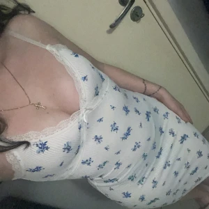 Två korta spetsklänningar med smala axelband - Säljer två söta kortklänningar med smala axelband. Ena är vit med blått blommönster, ribbad struktur och spetsdetaljer vid urringningen. Den andra är helsvart med spetskant upptill och figurnära passform. Perfekta för sommarens alla tillfällen. 120kr/styck. Båda för 200kr