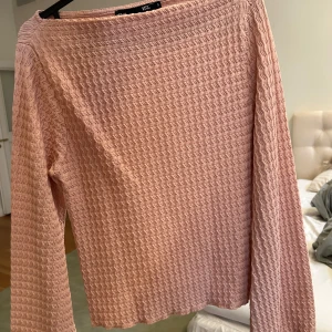 Rosa långärmad topp med struktur - Säljer en rosa långärmad topp från 157 med vågig struktur i tyget. Toppen har en rak passform och är tillverkad i ett mjukt material som känns skönt mot huden. Perfekt för dig som gillar en enkel men ändå unik look.