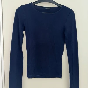 Mörkblå långärmad tröja Gina Tricot - Snygg mörkblå långärmad tröja från Gina Tricot i storlek XXS. Den passar bra på mig som vanligt har XS-S. Modellen är slim fit med rund hals och mjukt bomullsmaterial som sitter skönt mot kroppen. Perfekt att styla med jeans eller kjol för en enkel och clean look.