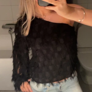Svart offshoulder topp från Gina Tricot - Säljer en svart offshoulder topp från Gina Tricot i storlek 38. Toppen har en lång ärm och är täckt av coola fransdetaljer som ger en unik look. Materialet är lätt och syntetiskt, använd fåtal gånger!!