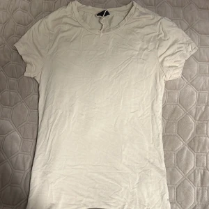 Vit/beige  t-shirt från Gina Tricot - En enkel och stilren vit/beige t-shirt från Gina Tricot i storlek S. T-shirten har rund halsringning och korta ärmar. Materialet känns mjukt och lätt, 