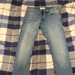 Ljusblå jeans från Stock & Hank - Snygga ljusblå jeans från Stock & Hank Supply Company med klassisk femficksdesign och raka ben. Jeansen har normal passform, gylf med dragkedja och knapp, samt detaljerade sömmar. Perfekta för dig som gillar en enkel och stilren look.