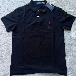 Svart piké från Polo Ralph Lauren - Svart pikétröja från Polo Ralph Lauren med klassisk krage och två knappar framtill. Custom slim fit-modell med röd broderad logga på bröstet. 