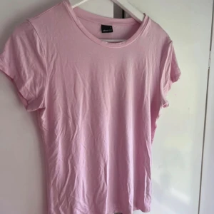 Ljusrosa t-shirt från Gina Tricot - Säljer en enkel och mjuk ljusrosa t-shirt från Gina Tricot i storlek L. T-shirten har rund hals och korta ärmar, perfekt för dig som gillar en clean och chill stil. Materialet är bomull som känns skönt mot huden.