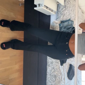 Svarta bootcut jeans med låg midja - Snygga svarta jeans med bootcut och låg midja. Jeansen har klassisk femficksdesign, smal passform över låren och lätt utsvängda ben. Perfekta till sneakers eller boots och ger en clean siluett. Materialet är stretchigt jeans för extra komfort.