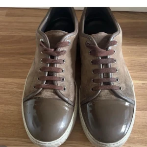 Lanvin skor - Snygga bruna sneakers med mocka på sidorna och glansig, lackad tå i mörkbrunt. Storlek 43-44 tvär feta, bara höra av dig vid frågor. Dunder skick. Pris kan diskuteras/byten är intressanta/Alex🫡