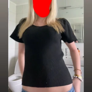 Svart ribbad topp med kort ärm - En svart ribbad topp med korta ärmar. Toppen har en enkel och stilren design som passar till många olika outfits. Materialet är stretchigt och bekvämt. Den är i storlek 134-140 men funkar som XS, eftersom materialet är väldigt stretigt