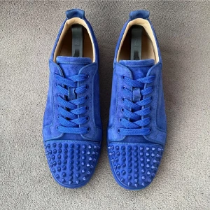 Blå mockasneakers från Louboutin - Snygga blå sneakers i mocka från Christian Louboutin med coola nitar på tån och klassisk röd sula. Skorna har snörning och rund tå, perfekt för dig som vill sticka ut med en lyxig och edgy stil.