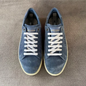 Saint Laurent blå mocka sneakers - Snygga blå sneakers från Saint Laurent i mocka med vit sula och vita snören. Skorna har handskriven Saint Laurent-logga på sidan och gulddetaljer vid snörningen. Perfekt för dig som gillar stilrena och exklusiva sneakers med en unik touch.