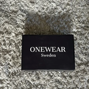 Randigt flätat bälte från ONEWEAR - Säljer ett snyggt flätat bälte från ONEWear Sweden. Bältet har ett randigt mönster i svart, grått och vitt med detaljer i svart skinn och ett stilrent metallspänne. Perfekt accessoar för att lyfta din outfit. storlek 90. kom dm vid frågor kan frakta inom kort.
