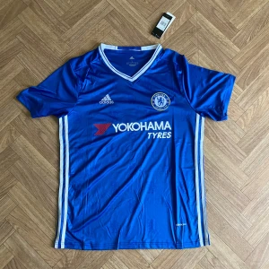 Chelsea 16/17 Hemmatröja – Eden Hazard #10 - Chelsea FC hemmatröja säsongen 2016/2017 med Hazard 10 på ryggen. Tröjan är i storlek L OBS kragen är lite stor och den passar dom som är mellan L och XL