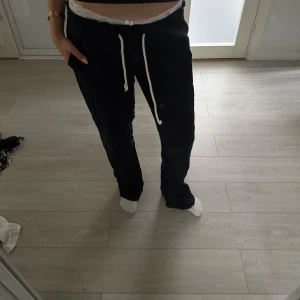 Svarta linnebyxor från Roxy - Svarta linnebyxor från Roxy med vit snörning i midjan. Byxorna har en avslappnad passform och är tillverkade i ett mjukt material som känns skönt mot huden. Perfekta för chill dagar eller när du vill vara bekväm men ändå se snygg ut.