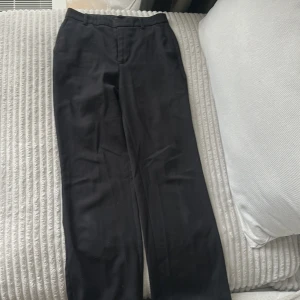 Svarta kostymbyxor  - Stilrena svarta kostymbyxor med raka ben och klassisk long flare passform, Byxorna har hällor för bälte, diskreta bakfickor och stängs med dragkedja och hake. Saknar en knapp (se bild) men passar utan , annars enkelt att sy dit en knapp! 
