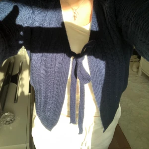  stickad kofta med knyt - fin mörkblå stickad kofta med kabelstickat mönster och framtill kan man knyta. Koftan har långa ärmar och en lite croppad passform. inte så stretchig så du vet.💕