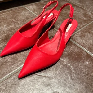 Röda pumps med spetsig tå från Nelly - Snygga röda pumps från Nelly med spetsig tå och öppen häl. Aldrig använda. 