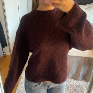 Mörk vinröd stickad tröja - Mysig stickad tröja i mörk vinröd färg. Tröjan har rund hals, långa ärmar och är tillverkad i ett mjukt stickat material som känns skönt mot huden. Perfekt för kyliga dagar och enkel att matcha med jeans eller kjol.