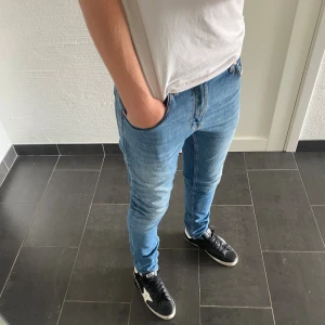 Tiger of Sweden Jeans - Säljer ett par ljusblå skinny jeans från Tiger of Sweden, modell Pistolero. Jag är 185 och väger 77kg på bilden. Jeansen har klassisk femficksdesign, snygga kontrastsömmar och är tillverkade i bomull. Perfekta för dig som gillar en tight passform och italiensk design.