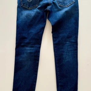 Mörkblåa jeans slimfit - Snygga mörkblå skinny jeans med klassisk femficksdesign och lätt slitning på låren. Jeansen har smal passform och normal midja, perfekta för en trendig och avslappnad look. Tillverkade i stretchigt denim för extra komfort. slimfit från replay