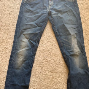 Blå Replay jeans straight fit w29 L29 - Säljer ett par klassiska blå jeans från Replay med snyggt slitna detaljer på knäna och bakfickorna. Jeansen har raka ben och normal passform, med fem fickor och tydliga sömmar. Perfekta för dig som gillar en tidlös och avslappnad look.