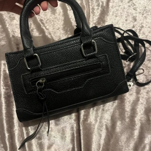 hand väska  -  Jättesnygg och stilren handväska med mycket plats. Har en längre rem så den kan bäras bekvämt på axeln. Rymmer allt man behöver till vardags – mobil, nycklar, smink, plånbok osv. (får även plats en liten vattenflaska ca 330 ml)