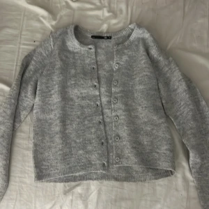 Grå kofta från 157 i stickad bomull - Mysig grå kofta från 157 i stickad bomull. Koftan har rund halsringning, långa ärmar och knäppning framtill, aldrig använd.