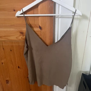 Beige linnetopp med v-ringning - Säljer en stilren beige linnetopp med smala axelband och djup v-ringning. Toppen har en lös passform och är tillverkad i ett lätt material. Passar S-M