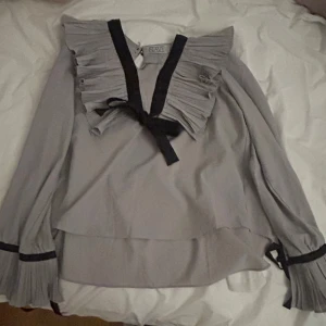 Rosett blus med volang - Fin volang blus med rosett fram. Storlek S-M och knappt använd.