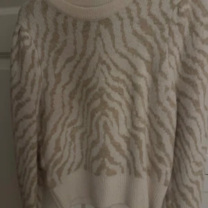 Beige zebramönstrad stickad tröja - Mysig stickad tröja i beige och vitt med zebramönster. Tröjan har rund halsringning, ribbade muddar och lång ärm. Perfekt för dig som gillar djurmönster och vill ha en trendig look. Aldrig använd och säljer den pårgrund av de, kom privat för fler bilder eller frågor🥰🥰