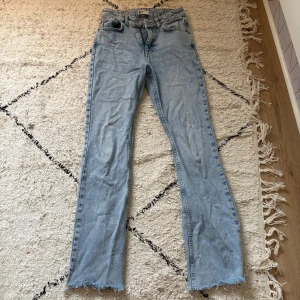 Ljusblå bootcut jeans från Gina Tricot - Ljusblå jeans med bootcut passform från Gina Tricot. Klassisk femficksmodell med råa, fransiga benslut och dragkedja. Jeansen är tillverkade i bomull och har en snygg, avslappnad vibe. Finns en fläck på framsidan av benet som syns på sista bilden!🥰❤️