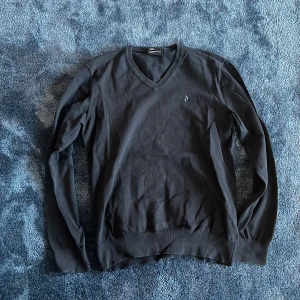 Svart v-ringad tröja Peak Performance - Svart v-ringad tröja från Peak Performance i storlek L. Tröjan har långa ärmar och ribbade muddar vid ärmslut och nederkant. Enkel och stilren design med liten logga på bröstet. Perfekt för lager-på-lager under kyligare dagar.