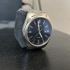 Klocka casio  - Stilren Casio klocka med blå urtavla och datumvisning. Klockan har ett klassiskt runt silverfärgat boett och matchande länkarmband i metall. Perfekt accessoar för dig som gillar en tidlös och snygg look. Nypriset ligger på ca 700. Den är bara använd två gånger 
