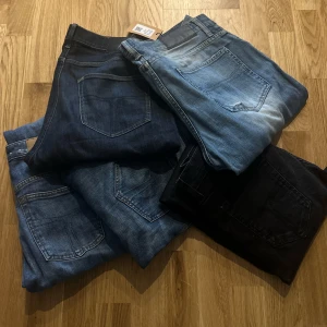 Stort parti jeans i olika tvättar - Säljer ett stort gäng jeans i olika blå och svarta tvättar. Modellerna varierar mellan slim och straight fit, flera med klassiska femficksdetaljer och läderpatch bak. Materialet är bomullsjeans, vissa med stretch. Perfekt för dig som vill ha många val i garderoben.