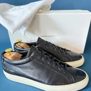 Common Projects Achilles Low 41 - Ikoniska lyxsneakers. För dig som tröttnat på att se ut som alla andra med Golden Goose, Oliver Cabell och Koio. Här är orginalet av minimalistiska sneakers. Stora i storleken, passar dig med 42. Skick enligt bilder. Tar bud. Skoblock får du med om du inte prutar.