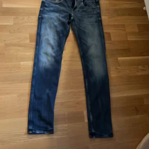 Blå Replay jeans, midwaist, tapered - Snygga blå jeans från Replay med klassisk tvätt och slitningar. Modellen har normal midja och avsmalnande ben, vilket ger en modern och clean look. Jeansen är tillverkade i slitstarkt denim och har fem fickor samt Replay-logga bak i midjan kan också byta för något pris kan diskuteras 