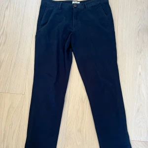 Marinblå chinos från Jack & Jones - Snygga marinblå chinos från Jack & Jones, modell Slim/Marco. Storlek 33/32.