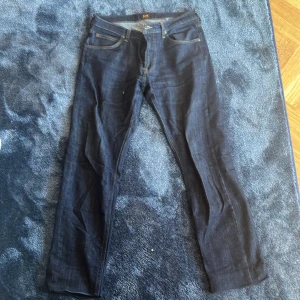 Mörkblå Lee Daren jeans W32 L32 - Säljer ett par mörkblå Lee Daren Zip Fly jeans i klassisk rak modell. Jeansen har fem fickor, dragkedjegylf och snygga kontrastsömmar. Perfekta för dig som gillar en tidlös och clean look. Materialet är slitstarkt denim i bomull.