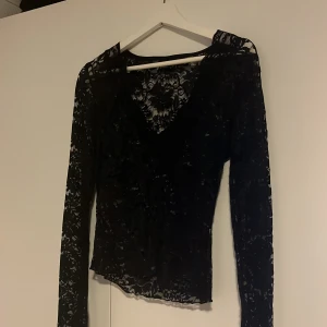 Svart spetsblus - Säljer en svart långärmad blus från Gina Tricot i genombruten spets med blommigt mönster. Toppen har v-ringning och är figurnära med transparenta ärmar. Säljer då den inte kommer till användning längre 💗bara använd några fåtal gånger, som i nyskick!