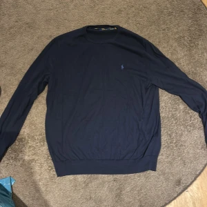 Marinblå långärmad tröja Polo Ralph Lauren - Snygg marinblå långärmad tröja från Polo Ralph Lauren i slim fit. Tillverkad i mjuk pima bomull och prydd med den klassiska broderade loggan på bröstet. Perfekt för dig som gillar stilren och enkel design. Priset kan diskuteras!