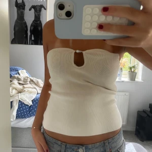 Beige bandeau tubtopp med pärldetalj - Säljer en beige bandeau tubtopp med ribbad struktur och en snygg pärldetalj! Prislapp kvar! Nypris 279💓🙌