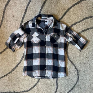 Rutig skjorta Tommy Hilfiger - Riktigt snygg rutig skjorta från Tommy Hilfiger i blått, vitt och röda detaljer. Skjortan har knappar framtill, två bröstfickor med lock och knapp samt uppvikbara ärmar med knapp. Perfekt för en avslappnad men stilren look.