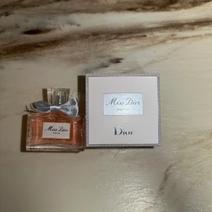 Miss Dior Parfum 80ml från Dior - Miss Dior Parfum från Dior i en elegant glasflaska med ljusrosa doft och en söt silverfärgad rosett vid halsen. Flaskan har en stilren, fyrkantig form och kommer med originalkartong i vitt och silver. Lyxig och feminin signaturdoft.
