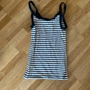 Randig linnetopp med marinblå detaljer - Ribbat linne med svarta och vita ränder.