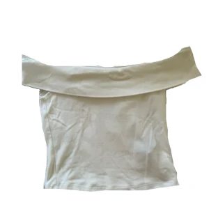 Vit offshoulder topp - Stilren vit offshoulder topp. Toppens enkla design gör den lätt att matcha och den har en figurnära passform. Perfekt för dig som gillar minimalistisk stil.