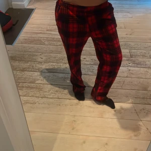 Röda rutiga byxor från EP Collection - Säljer ett par röda byxor med svart rutigt mönster från EP Collection. Byxorna har rak passform och elastisk midja för skön känsla. Perfekta för dig som gillar att sticka ut med färg och mönster. Materialet är mjukt och passar chill dagar.